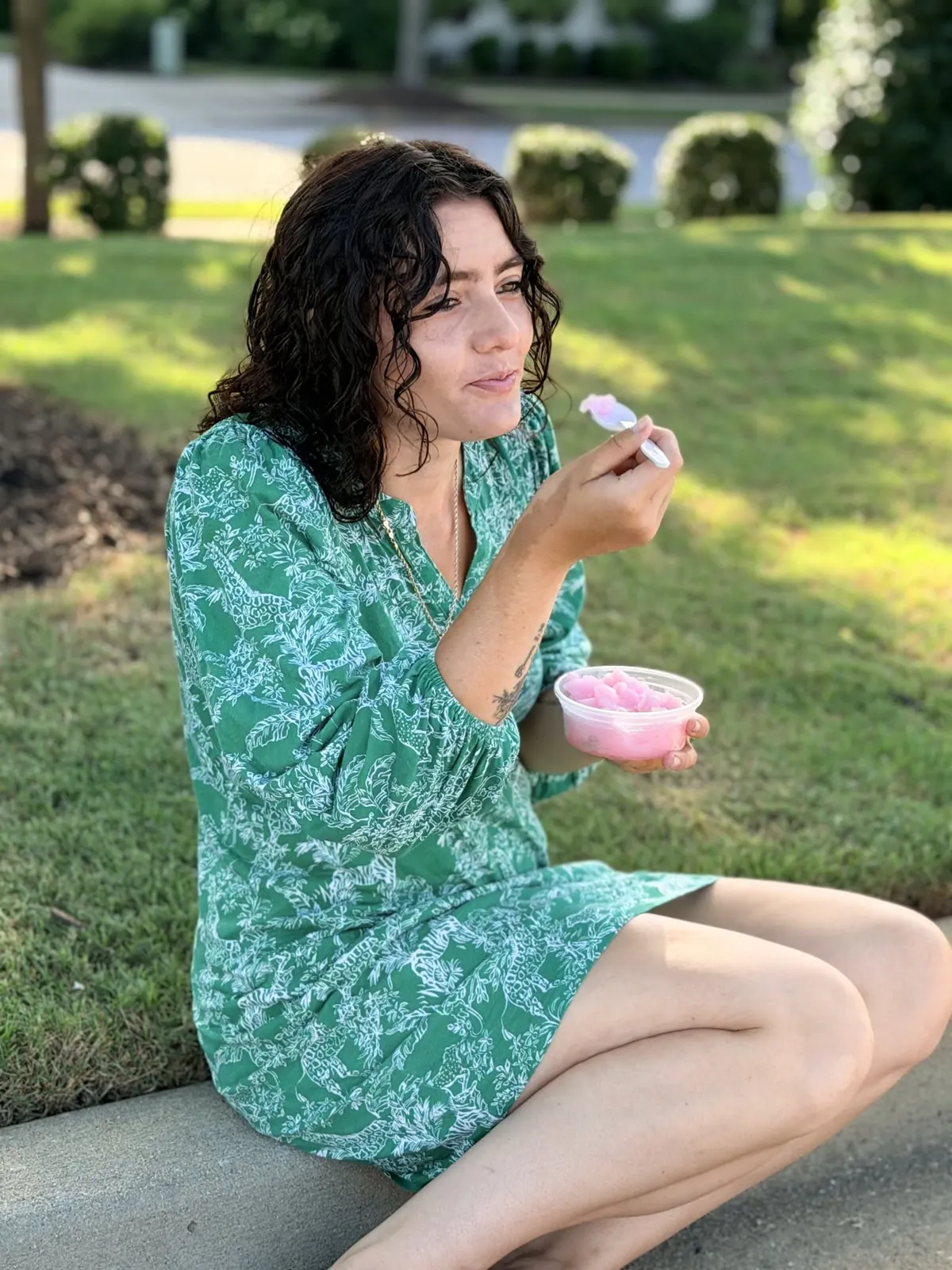 Helena enjoying a cup of pink Italian ice on the grass