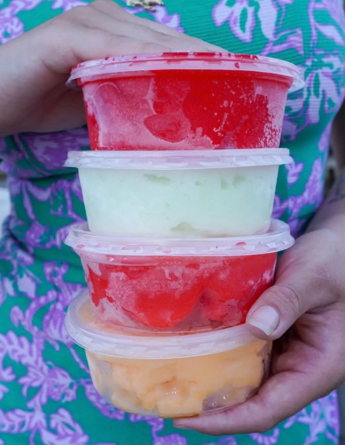 A stack of Italian ice cups in cherry, lime, strawberry and mango